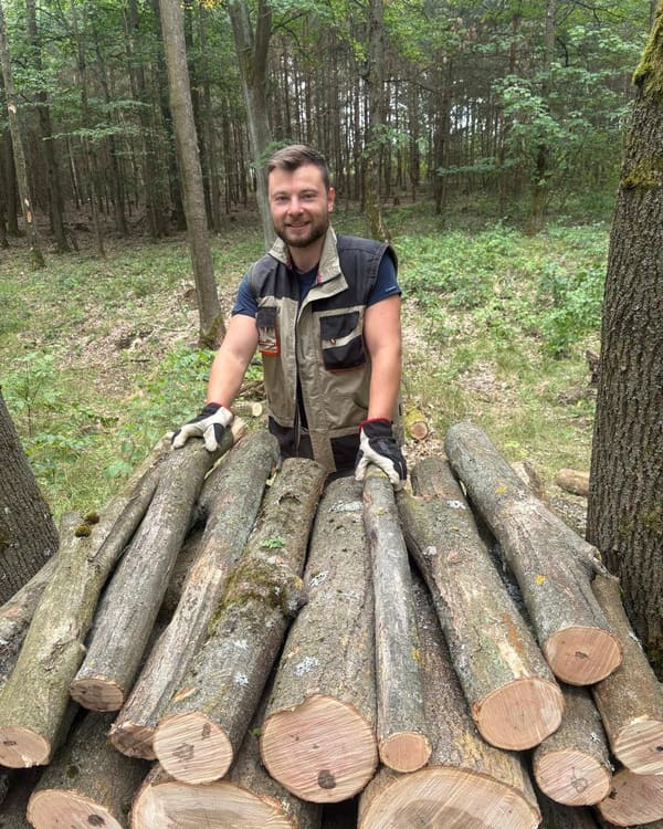 Tomáš Bouda v lese u připraveného dřeva